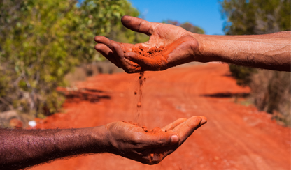Red earth falling from one hand to another